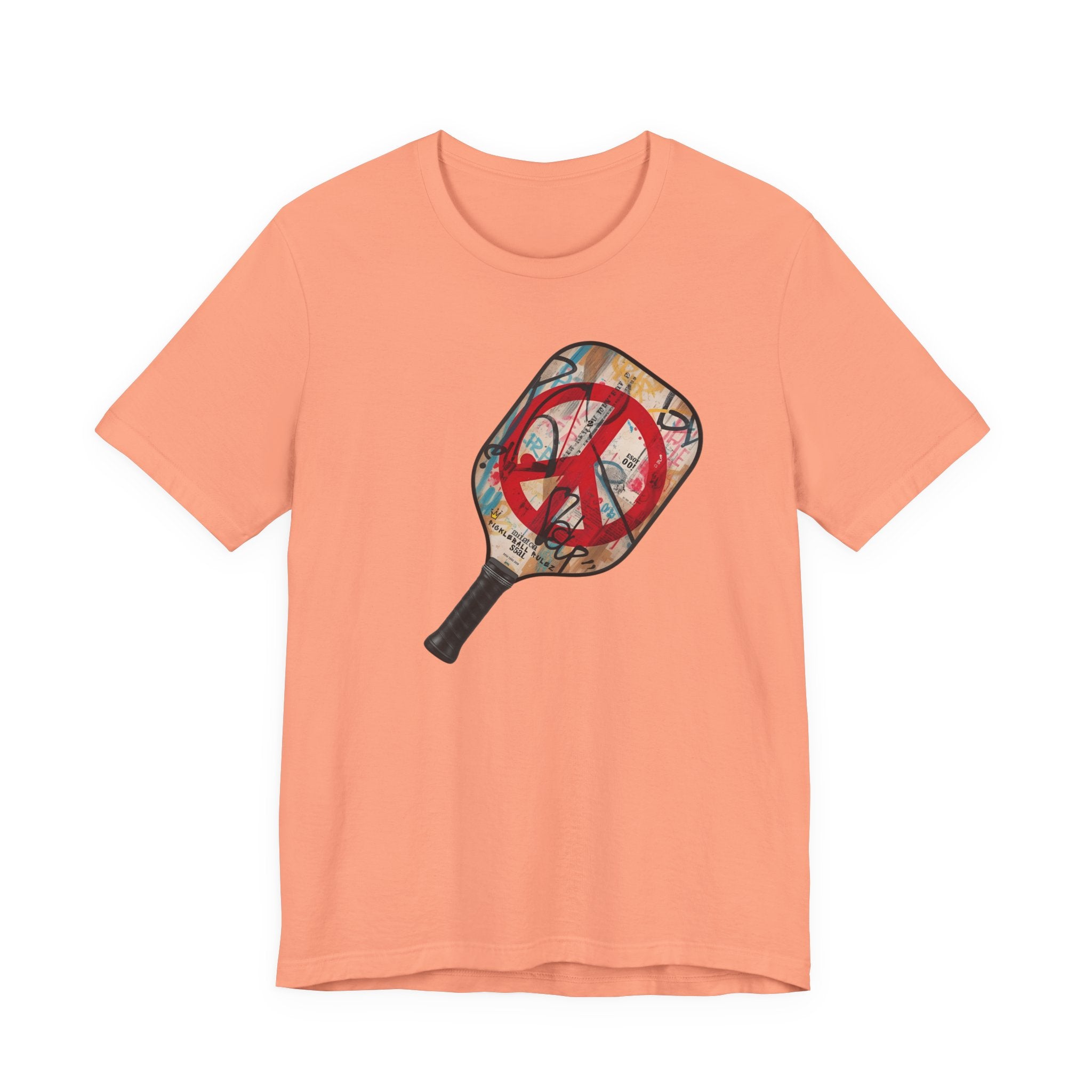 Peach t-shirt with a pickleball paddle design featuring a peace symbol on a white background