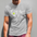Man wearing a gray t-shirt with a graphic design standing against a gray wall.