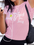 Woman in pink 'LOVE' t-shirt with earphones and phone, against a white wall.