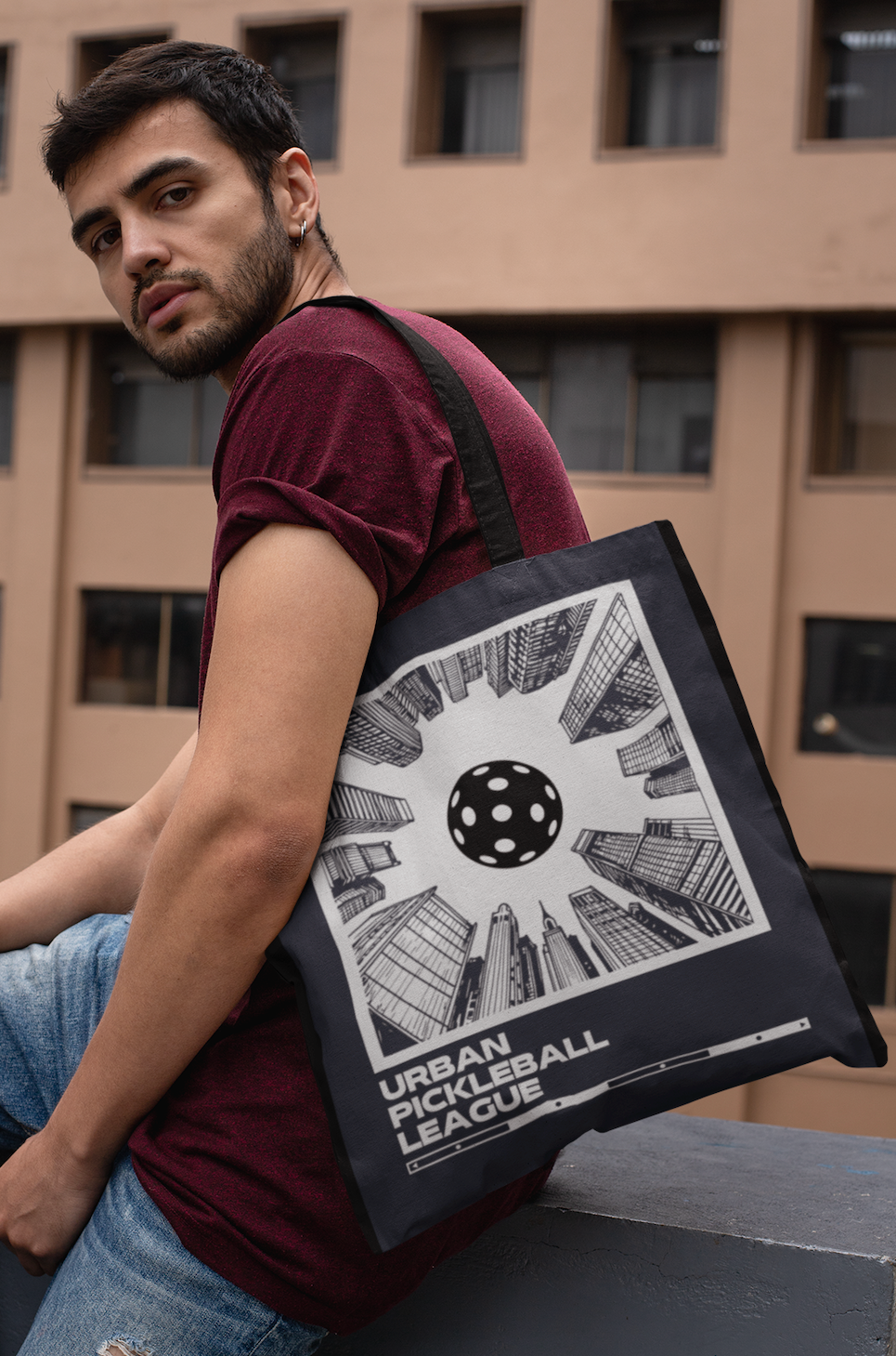 Man holding a tote bag with a geometric design against an urban background