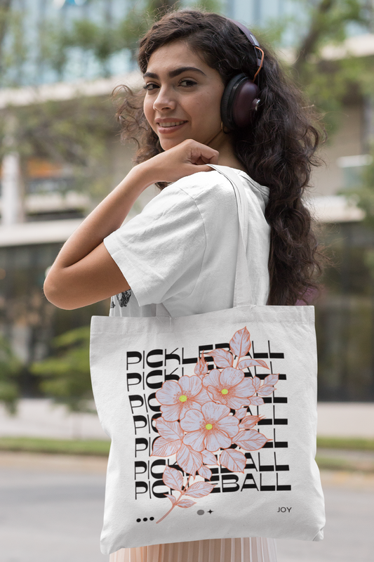 Woman wearing headphones and holding a tote bag with a floral design and text.