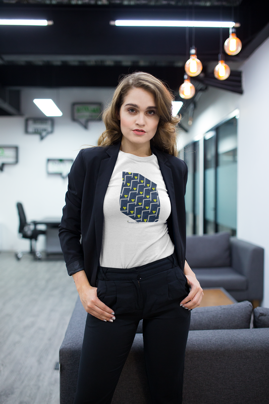 Woman standing in an office setting wearing a white t-shirt with a blue graphic design.