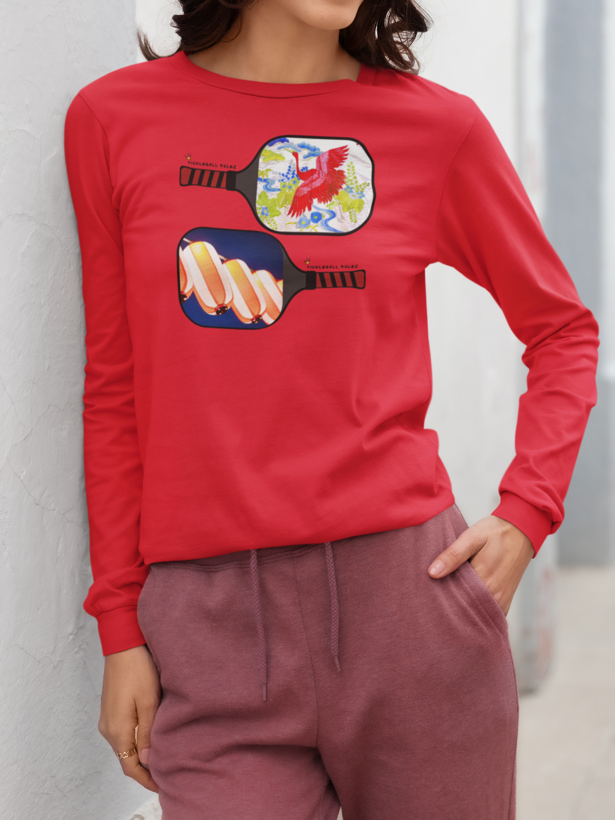 Person wearing a red long-sleeve shirt with colorful pickleball paddle design against a light gray background