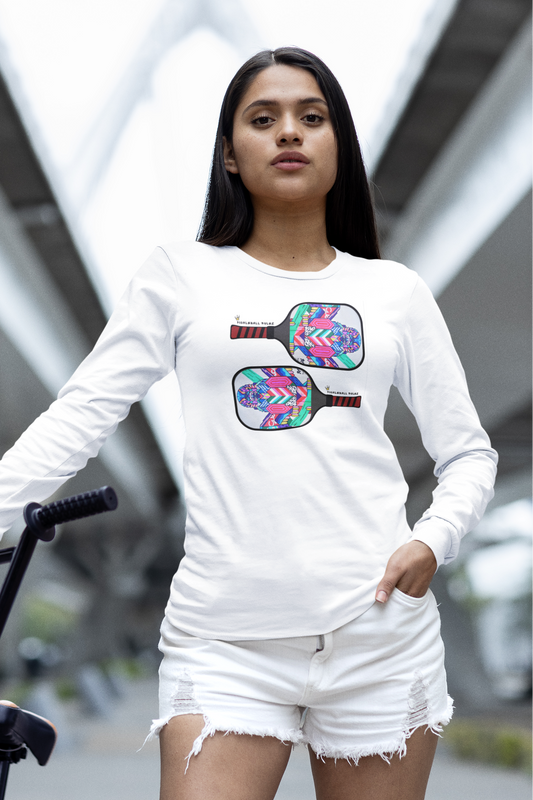 Woman wearing a white long-sleeve shirt with a colorful graphic design, standing next to a bicycle.