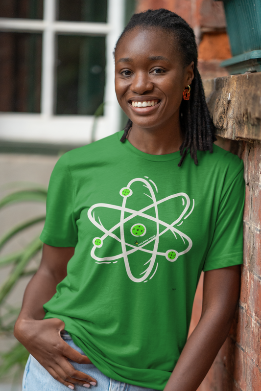 Person wearing a green t-shirt with an atom symbol, standing against a brick wall.