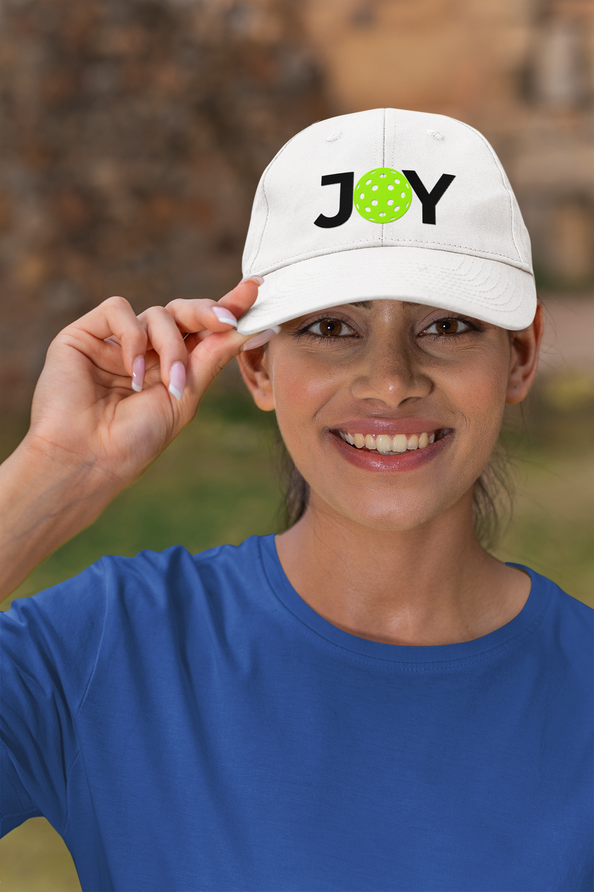 Person wearing a white cap with 'JOY' printed on it, outdoors.