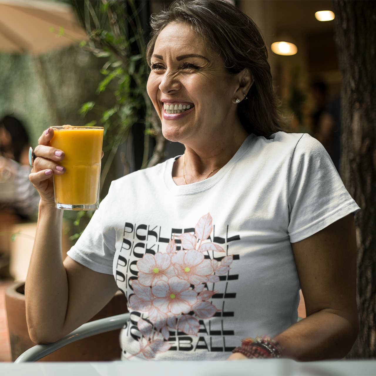 Woman holding a glass of orange juice outdoors in a casual setting