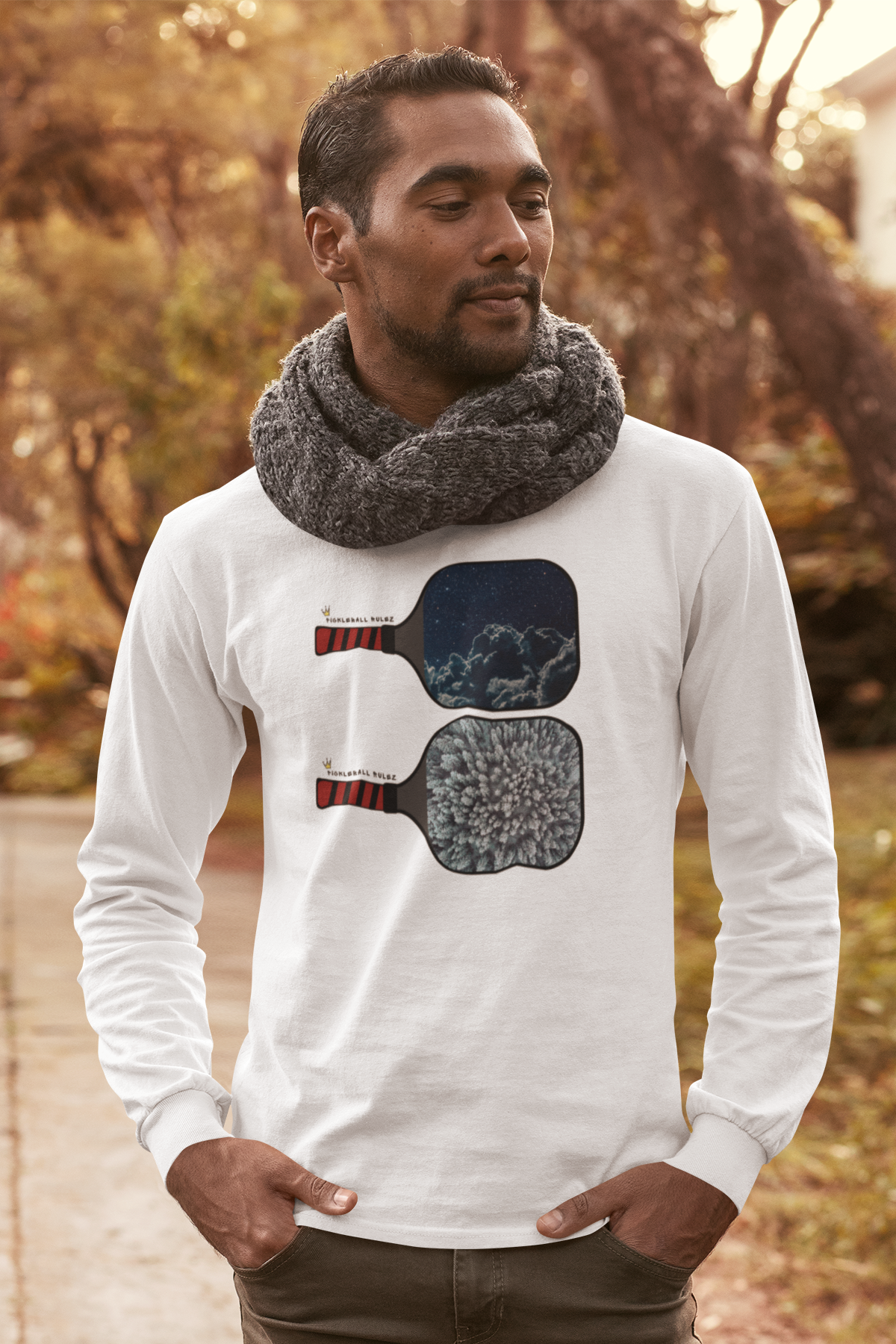 Man wearing a white long-sleeve shirt with a graphic design outdoors.