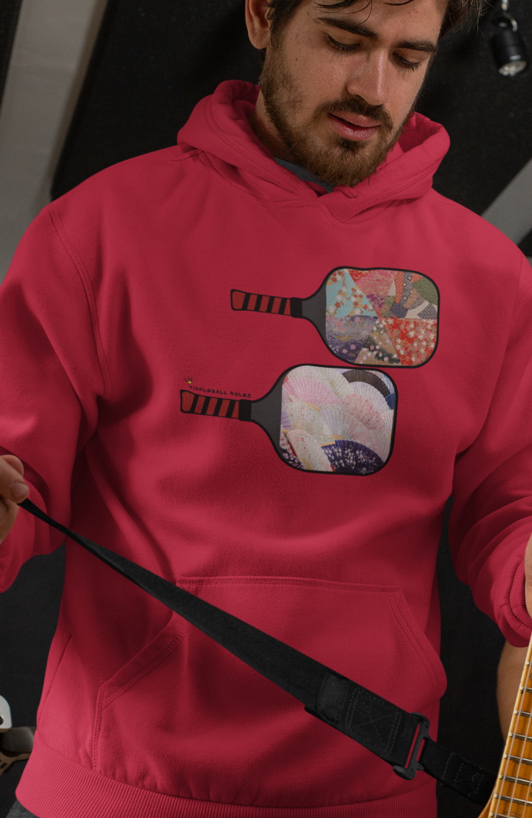 Person wearing a pink hoodie with guitar design holding a guitar