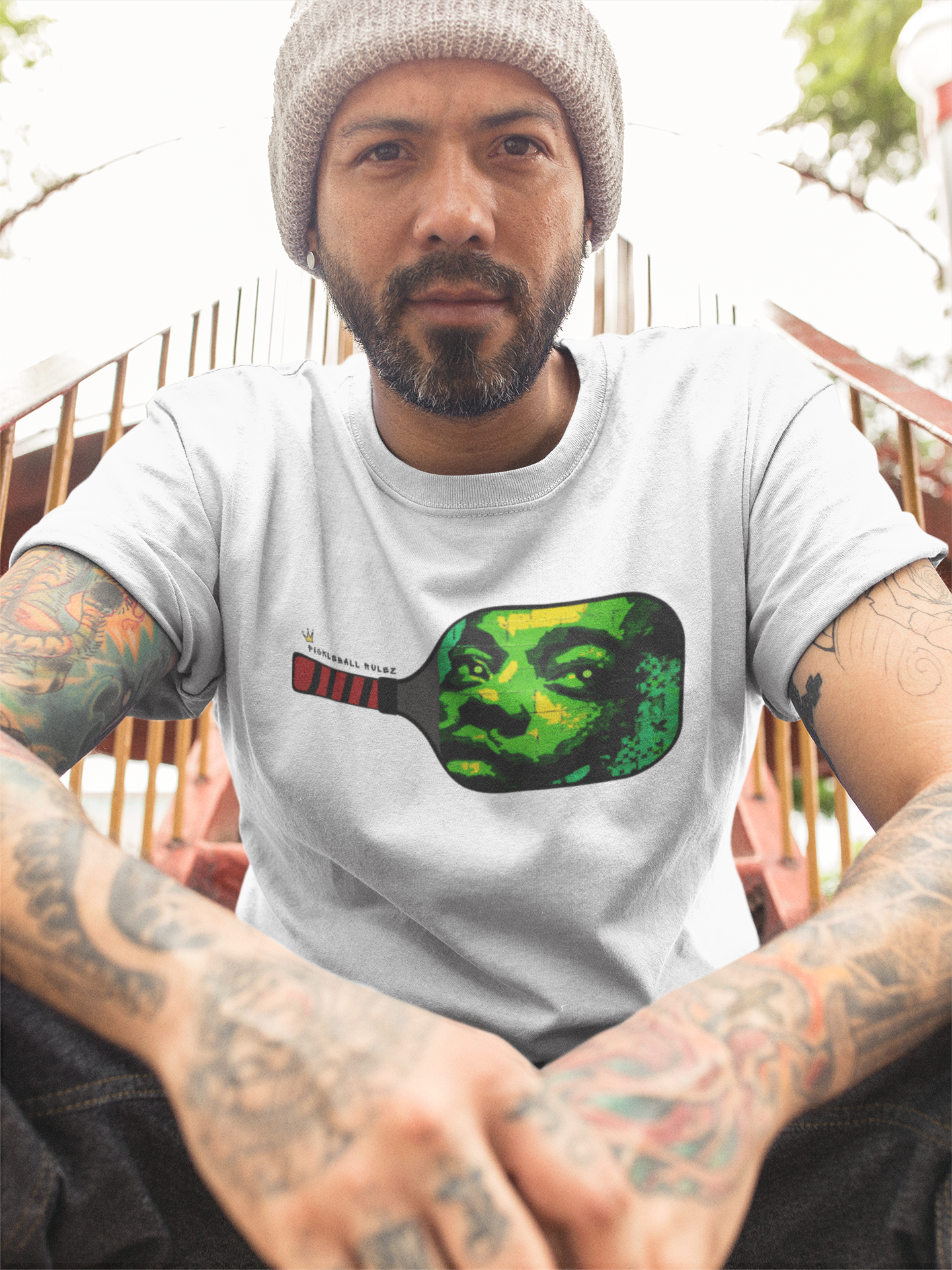 Man wearing a white t-shirt with a graphic design, sitting outdoors.