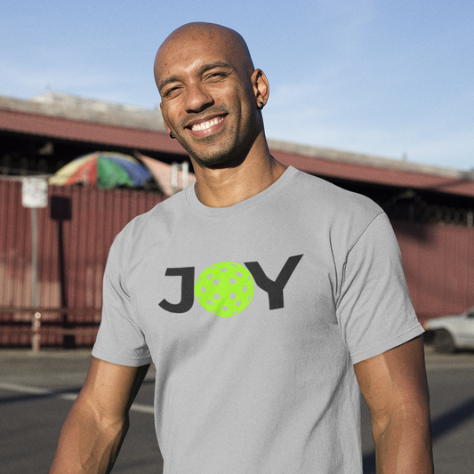 Man wearing a gray t-shirt with 'JOY' printed on it, standing outdoors.