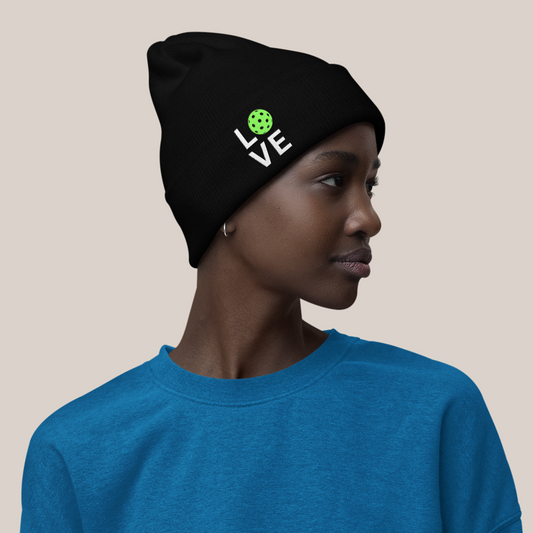 Person wearing a blue sweater and black shorts with a black beanie on a beige background