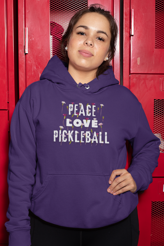 Person wearing a purple hoodie with 'Peace Love Pickleball' text in front of red lockers.