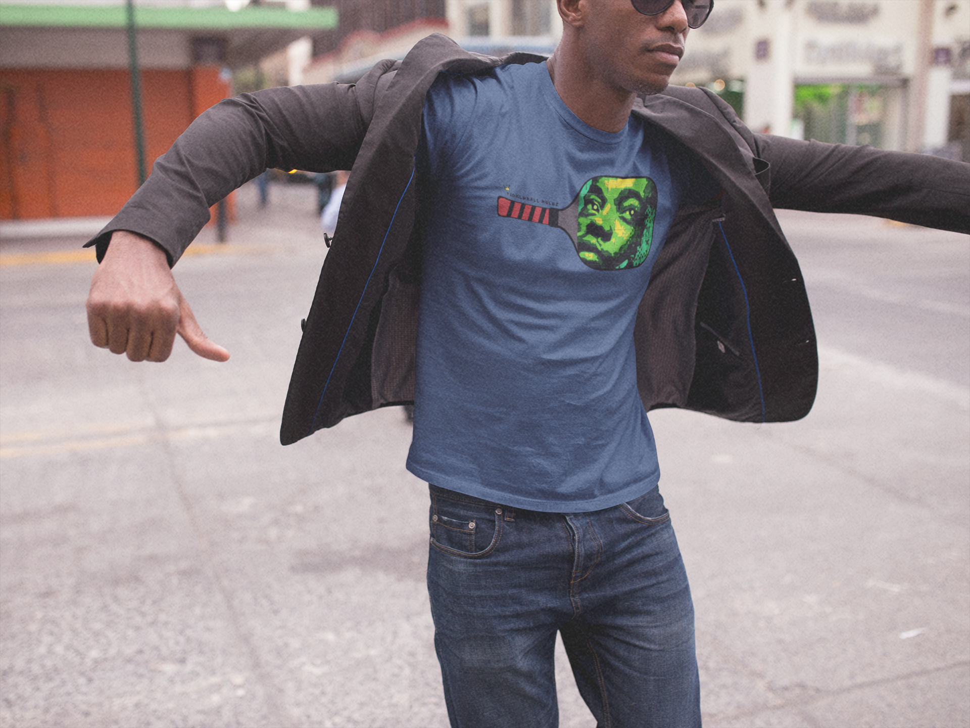 Man wearing a blue t-shirt with a graphic design, standing on a street.