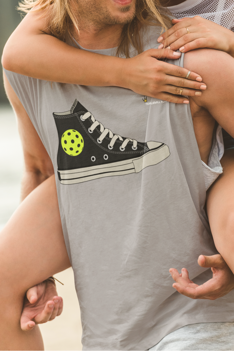 Man carrying a woman with a graphic of a black sneaker on his shirt, outdoors.