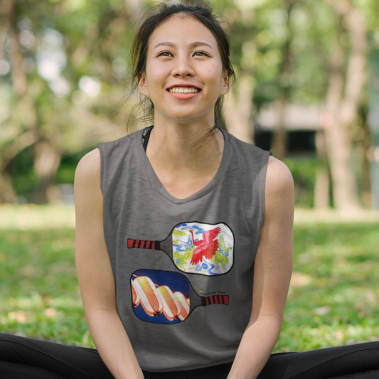 Woman sitting on a yoga mat in a park wearing a sleeveless shirt with colorful designs.
