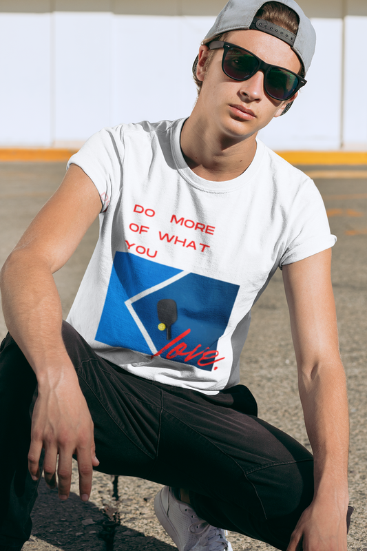 Person wearing a white t-shirt with graphic design and text, sitting outdoors.