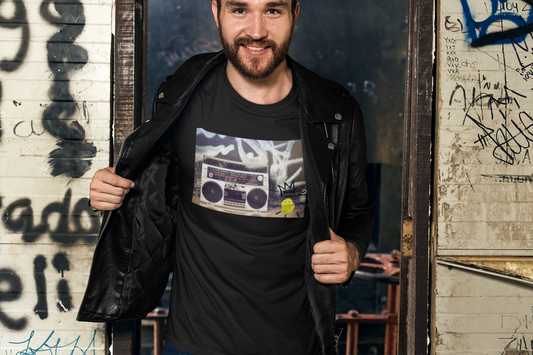Man wearing a black t-shirt with a graphic design, standing in front of a graffiti-covered wall.