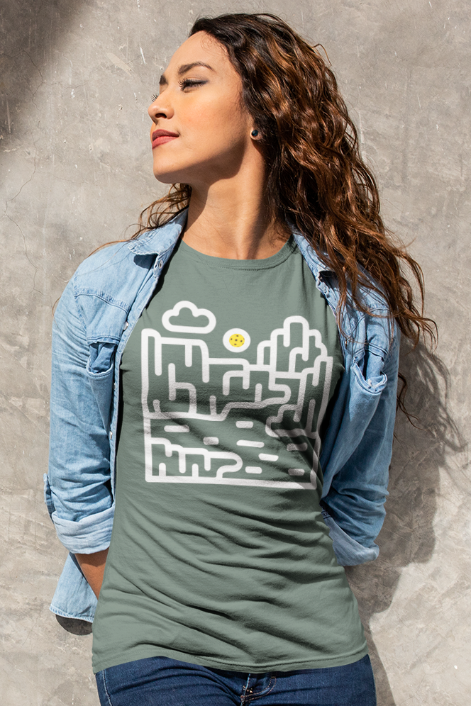 Woman wearing a green t-shirt with a graphic design against a textured wall.