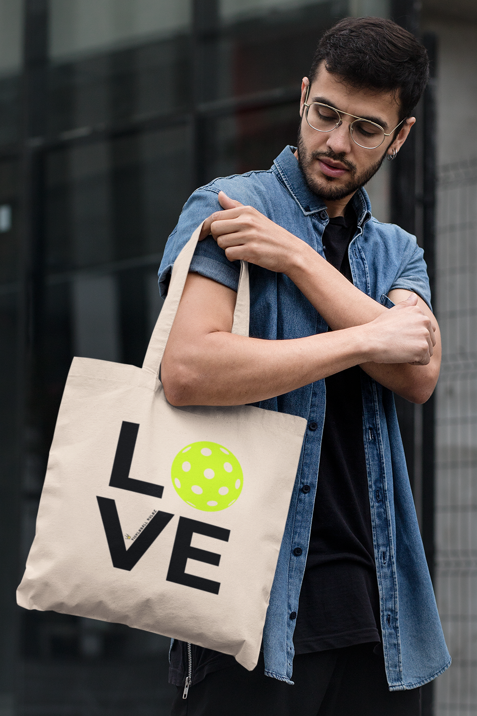 Man holding a tote bag with 'LOVE' printed on it in an urban setting