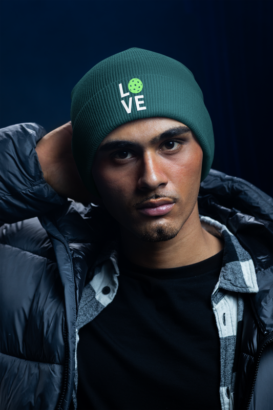 Person wearing a green beanie with 'LOVE' printed on it against a dark background